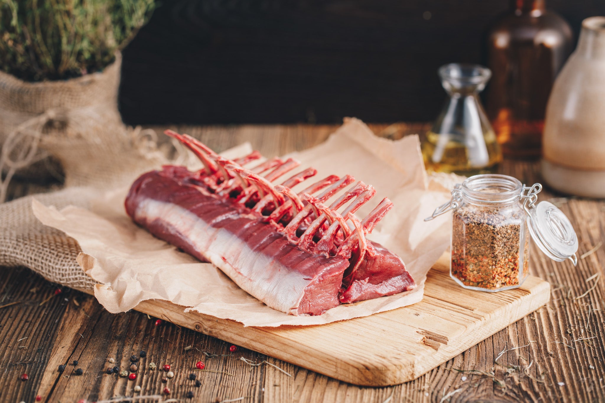 Ager Tirol Rehfleisch Rehracks Rehkarree ganzes Stück auf Holzbrett und rustikalem Hintergrund