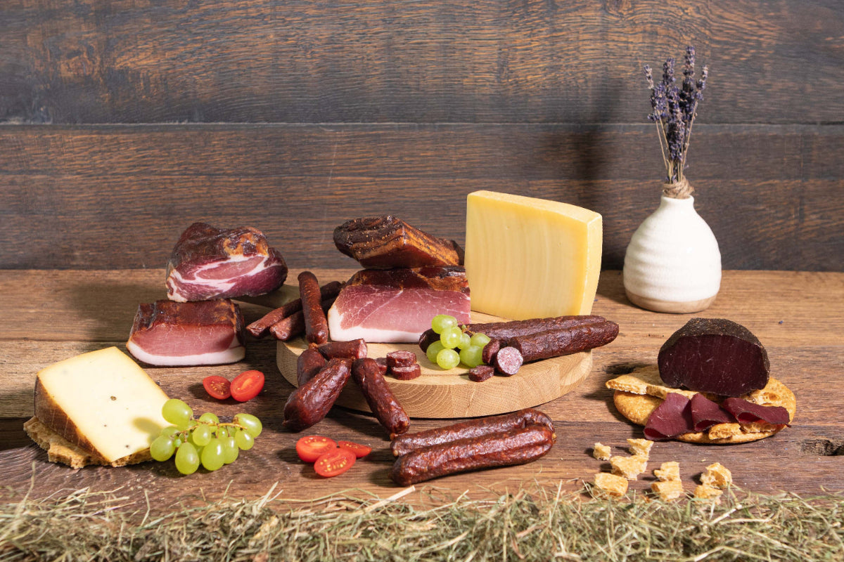 Käse Speck Paket Tiroler Jause würzig auf Brett und Heu rustikal