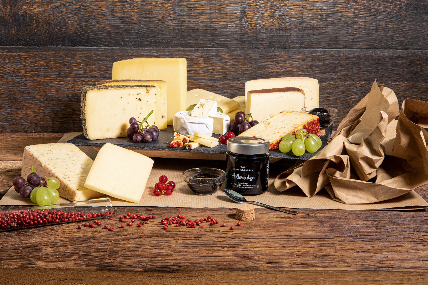 Genusswelt Tiroler Jause Käsepaket Käseschmaus mehrere Käsestücke aus Tirol und Marmelade auf Brett und Heu rustikal